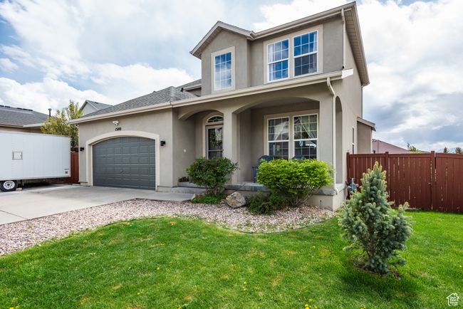 Traditional-style home featuring stucco siding, concrete driveway, an attached garage, and covered porch | Image 47
