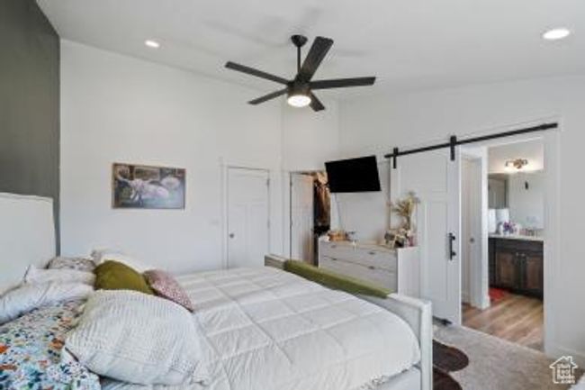 Bedroom with a barn door, recessed lighting, a ceiling fan, wood finished floors, and high vaulted ceiling | Image 18