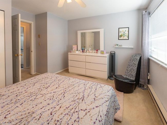 Bedroom with a ceiling fan, light carpet, baseboards, and baseboard heating | Image 17