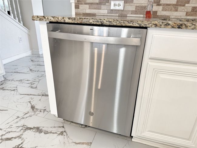 Kitchen view of stainless steel dishwasher, dark stone countertops, and white cabinetry | Image 16