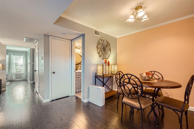 Dining area with baseboards, dark wood finished floors, crown molding, and a chandelier | Image 6
