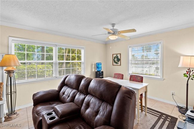 Living area featuring light tile patterned flooring, a textured ceiling, ornamental molding, and a ceiling fan | Image 6