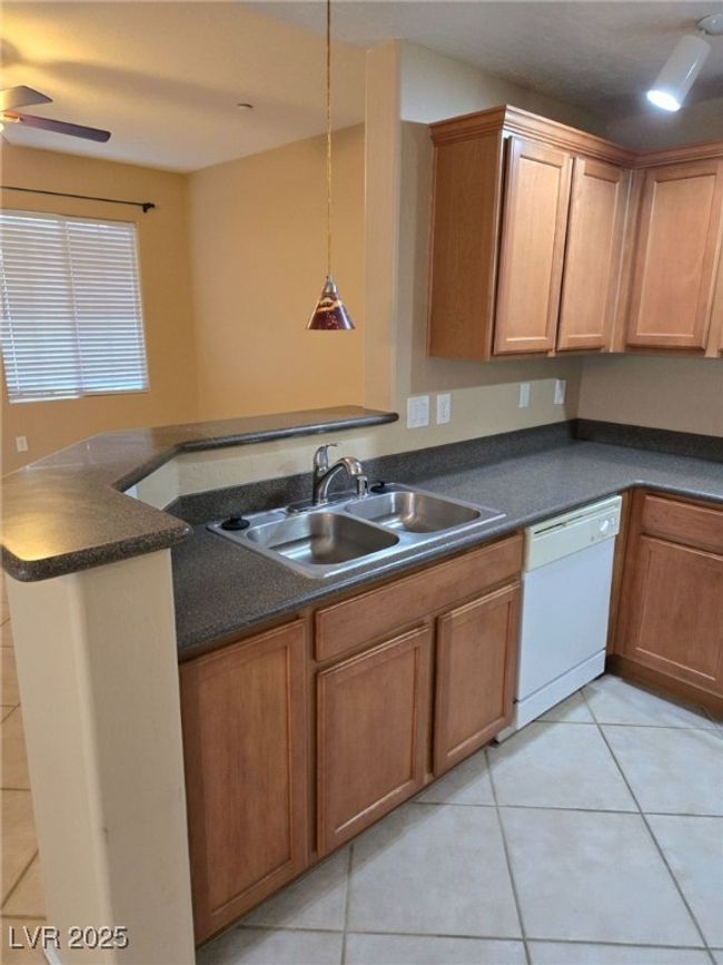 Kitchen featuring light tile patterned floors, white dishwasher, and a sink | Image 5