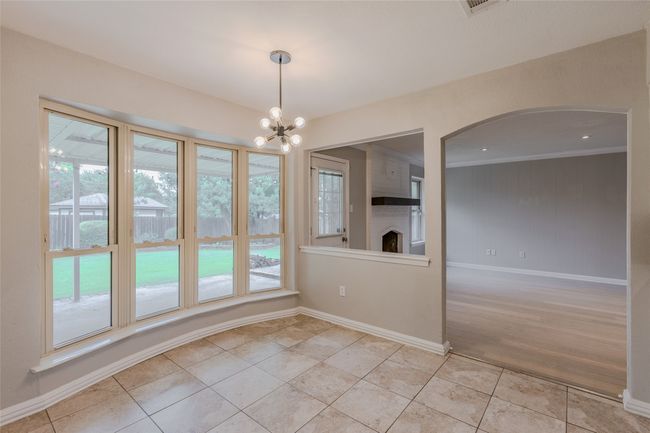 Unfurnished dining area with plenty of natural light, light tile patterned floors, a chandelier, ornamental molding, and arched walkways | Image 12