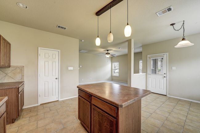 Kitchen featuring a center island, pendant lighting, a ceiling fan, and brown cabinets | Image 13