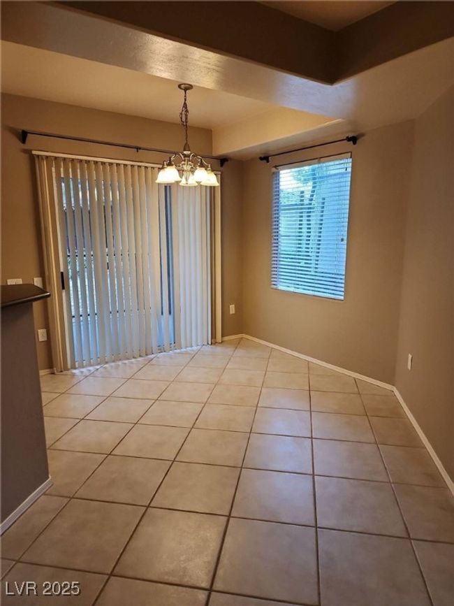 Empty room with light tile patterned floors, a chandelier, and baseboards | Image 17