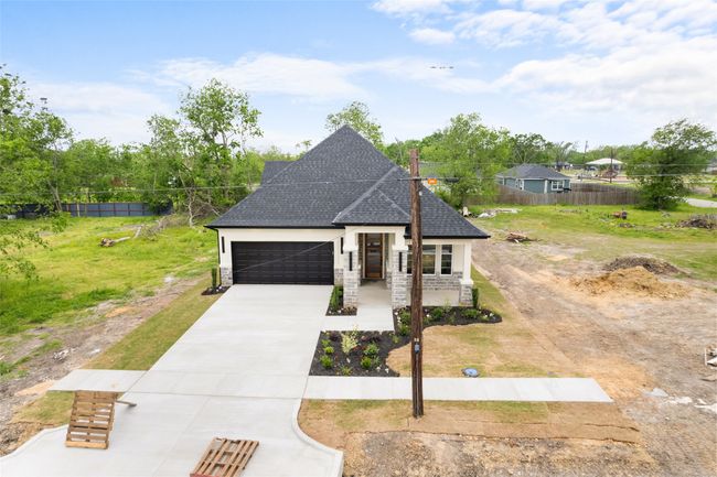 French provincial home featuring a garage, fence, stone siding, a shingled roof, and driveway | Image 27