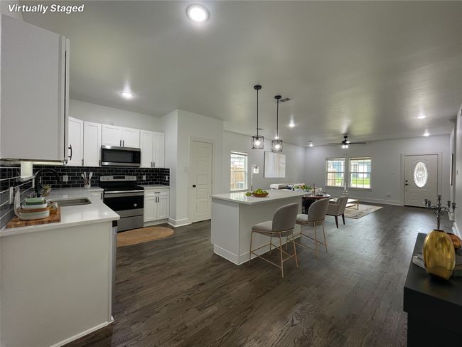 Kitchen with a sink, appliances with stainless steel finishes, dark wood-type flooring, and backsplash | Image 13