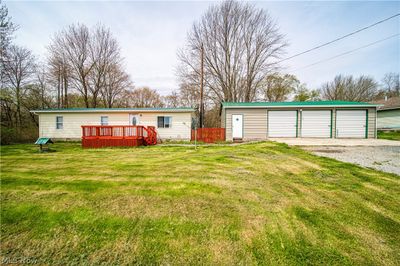 View of front of house with a 3 bay garage, a front lawn, a wooden deck and gate | Image 1