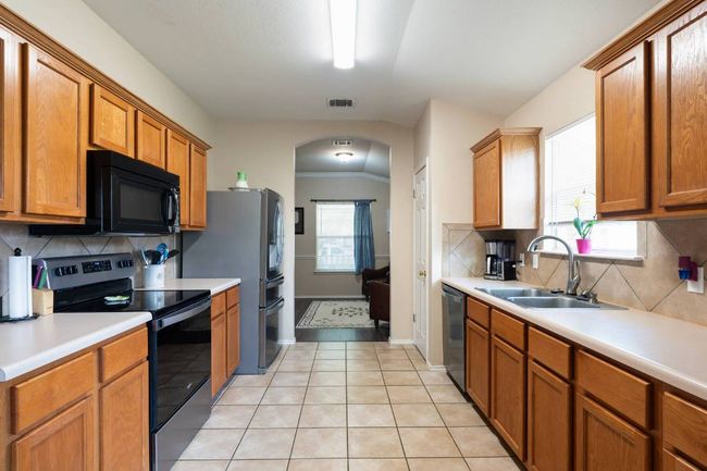 Kitchen with tasteful backsplash, range with electric stovetop, light countertops, arched walkways, and light tile patterned floors | Image 4