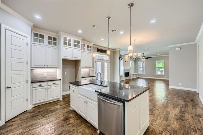 Kitchen featuring wall chimney exhaust hood, dark countertops, stainless steel appliances, dark wood finished floors, and recessed lighting | Image 6