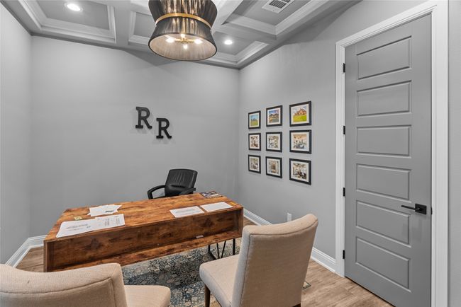 Home office featuring light wood-style flooring, coffered ceiling, ornamental molding, beam ceiling, and recessed lighting | Image 5
