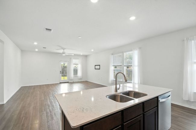Kitchen with dark wood-style flooring, recessed lighting, a kitchen island with sink, dark brown cabinets, and open floor plan | Image 12