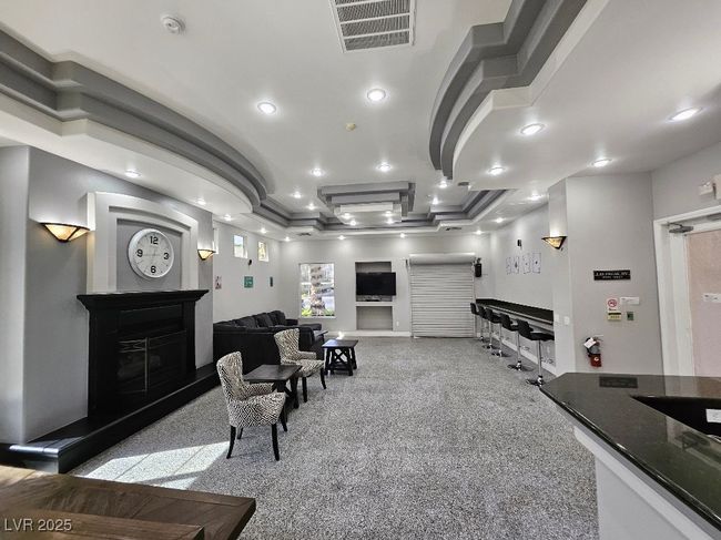 Living room with a fireplace with raised hearth, visible vents, ornamental molding, and recessed lighting | Image 10