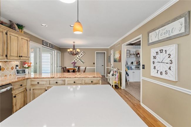 Kitchen featuring pendant lighting, light brown cabinetry, stainless steel dishwasher, a notable chandelier, and light hardwood / wood-style floors | Image 15
