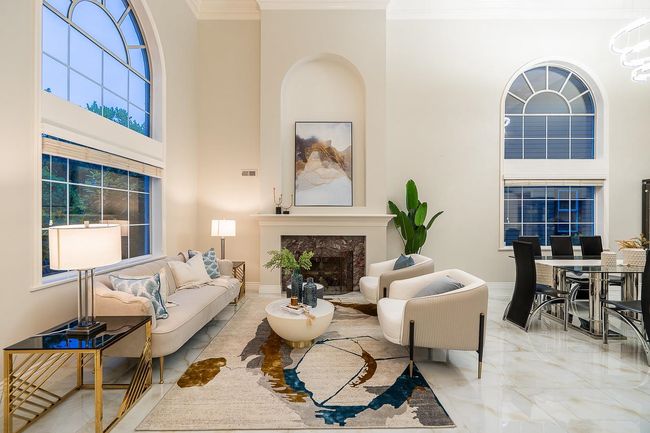 Living room with ornamental molding, marble tiled flooring, a towering ceiling, a fireplace, and baseboards | Image 6