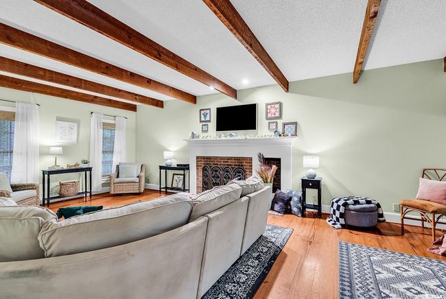 Living room featuring a brick fireplace, beamed ceiling, and light wood-style flooring | Image 4