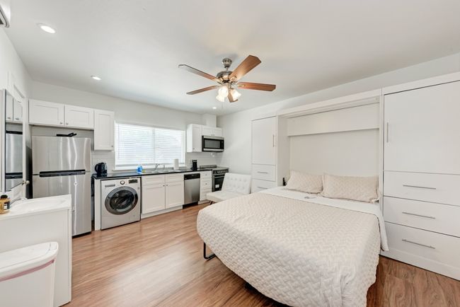 Bedroom with washer / clothes dryer, freestanding refrigerator, light wood finished floors, recessed lighting, and a ceiling fan | Image 4