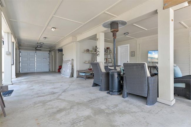 This photo showcases a spacious, covered patio area, adjacent to a garage. It offers a versatile space for relaxation or entertaining, protected from the elements and adjacent to the multipurpose downstairs room! | Image 4