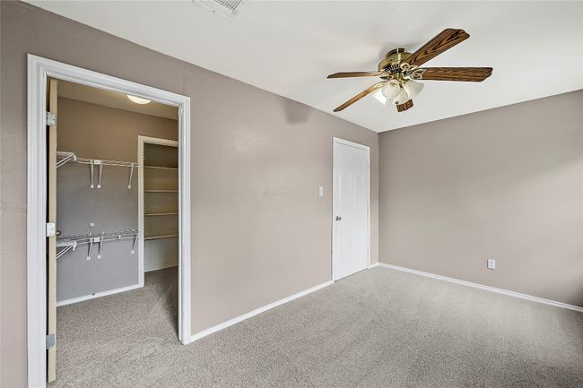 Unfurnished bedroom with carpet flooring, a spacious closet, and ceiling fan | Image 24