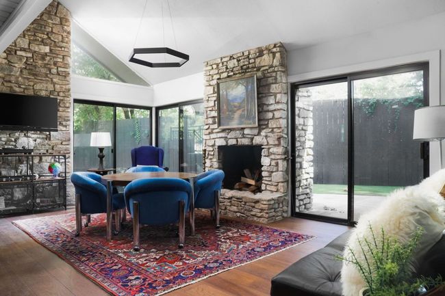 Living room with a stone fireplace, high vaulted ceiling, and wood finished floors | Image 14