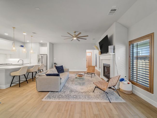 Living area featuring a glass covered fireplace, light wood-style floors, and ceiling fan | Image 6