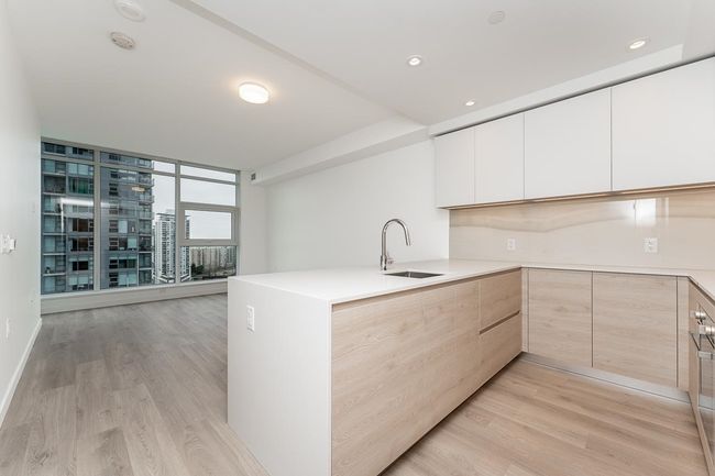 Kitchen with modern cabinets, a peninsula, light wood-type flooring, a sink, and light brown cabinets | Image 7