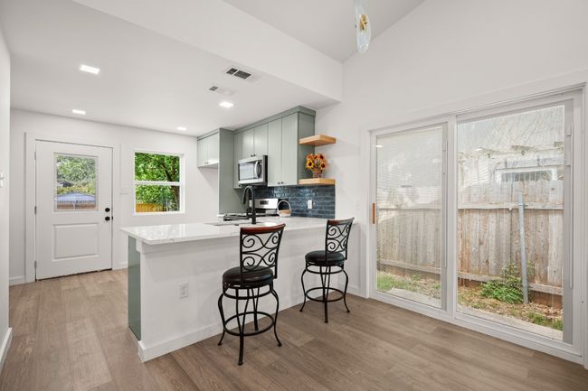 Kitchen featuring appliances with stainless steel finishes, open shelves, light wood-style floors, a peninsula, and tasteful backsplash | Image 8