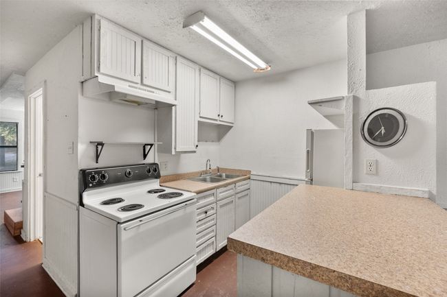 Kitchen with white appliances, white cabinets, under cabinet range hood, and light countertops | Image 9