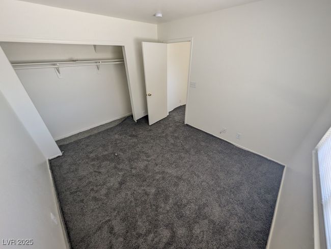 Unfurnished bedroom with dark colored carpet and a closet | Image 15