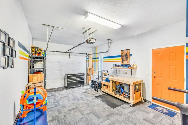 Garage with a workshop area and a garage door opener | Image 24
