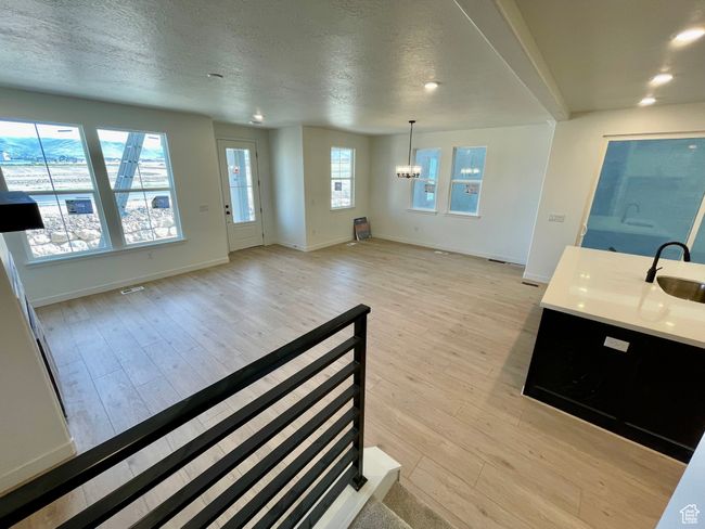 Unfurnished living room featuring a chandelier, light wood-style floors, a textured ceiling, and recessed lighting | Image 7