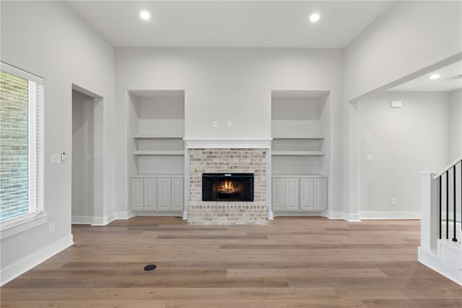 Unfurnished living room featuring light hardwood / wood-style flooring, a fireplace, and built in features | Image 8