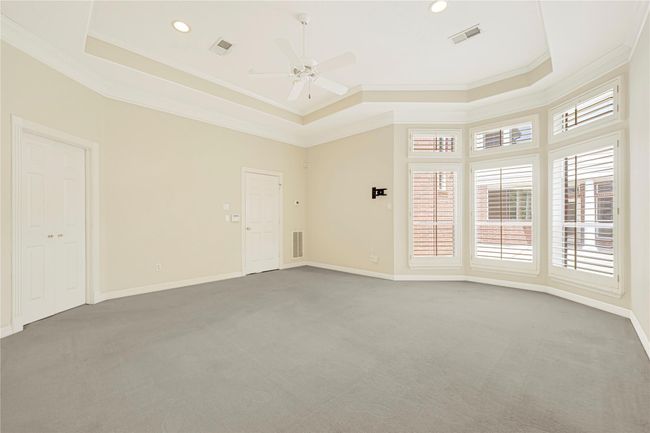 Spacious primary bedroom with elegant bay window and shutters. | Image 27