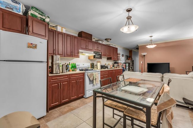 Kitchen with white appliances, crown molding, under cabinet range hood, pendant lighting, and decorative backsplash | Image 28