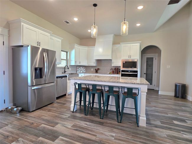 Kitchen with appliances with stainless steel finishes, arched walkways, white cabinets, a center island, and recessed lighting | Image 14