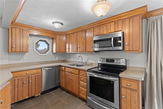 Kitchen with a sink, light countertops, brown cabinets, and appliances with stainless steel finishes | Image 11