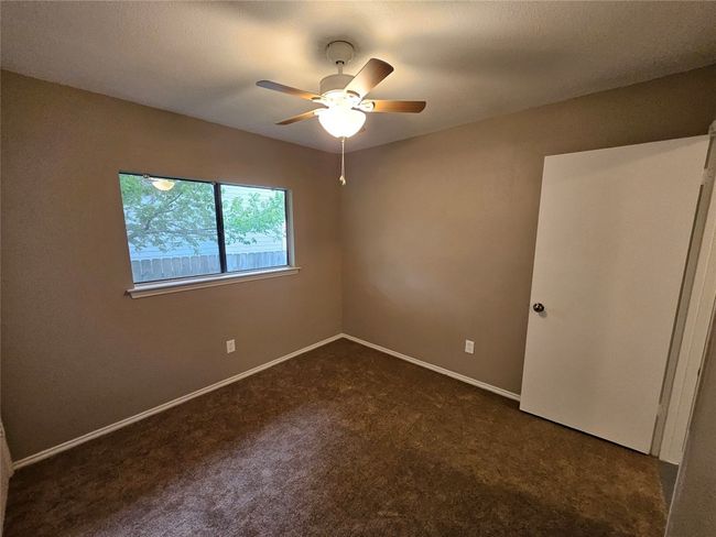 Empty room with baseboards, a ceiling fan, and dark carpet | Image 27