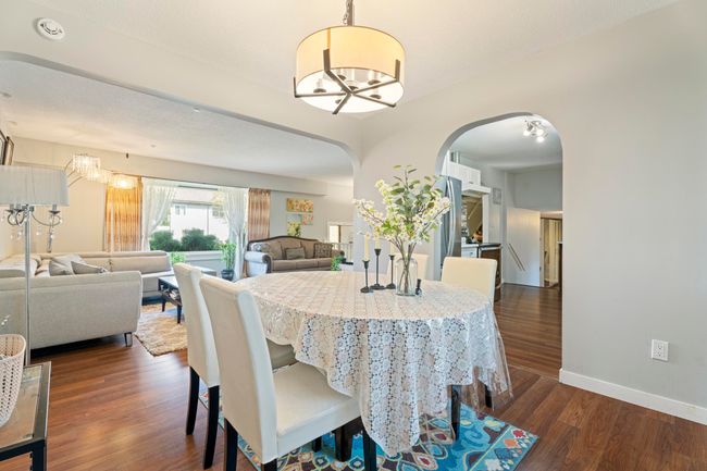 Dining space featuring dark wood-style flooring, baseboards, arched walkways, and an inviting chandelier | Image 11