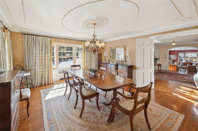 Dining area with arched walkways, a beautiful English design above the chandelier, wood finished floors. | Image 11