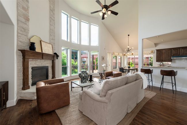 Living room with high vaulted ceiling, dark wood-style flooring, healthy amount of natural light, a fireplace, and a chandelier | Image 15