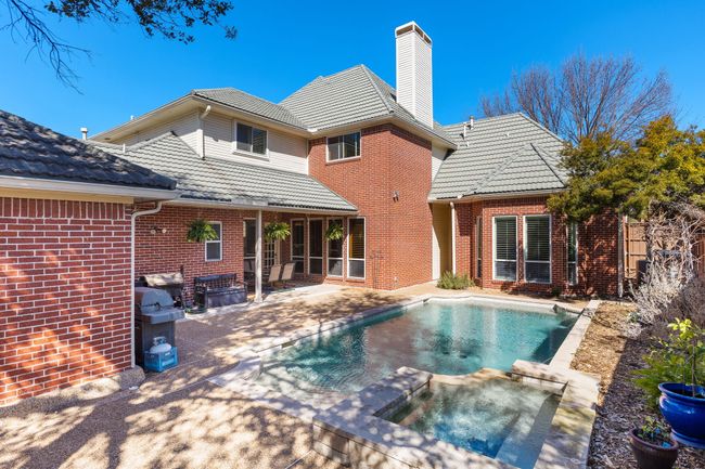 Rear view of property featuring a patio area, in ground hot tub, and brick siding | Image 31