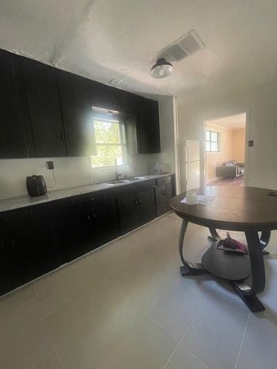 Kitchen with refrigerator, light tile patterned floors, and sink | Image 2