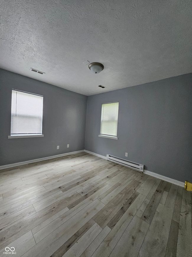 empty room with a baseboard heating unit, hardwood / wood-style flooring, baseboards, and a textured ceiling | Image 8