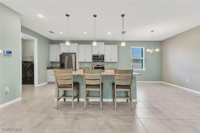 Kitchen featuring an inviting lighting, washing machine and clothes dryer, white cabinets, and stainless steel appliances | Image 21