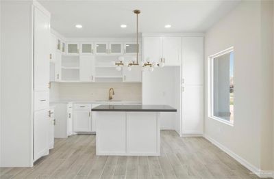 Kitchen with a center island, white cabinets, pendant lighting, and light hardwood / wood-style floors | Image 2