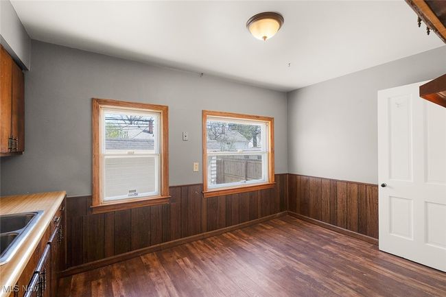 Unfurnished dining area with wooden walls, dark wood-style floors, and wainscoting | Image 7