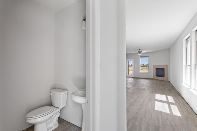 Bathroom with toilet, wood-type flooring, ceiling fan, and a tile fireplace | Image 9