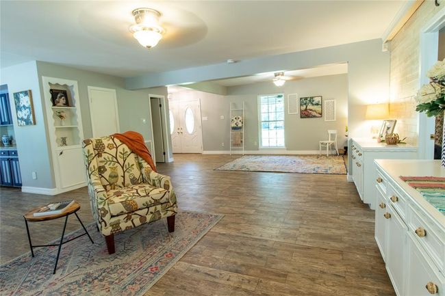 View looking from fire place wall of the den in the forefront toward the living room. The open door is the guest bath. The french doors are just beyond. | Image 8