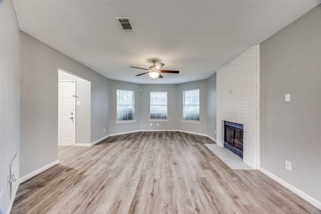 Unfurnished living room with light wood finished floors, a ceiling fan, and a brick fireplace | Image 4